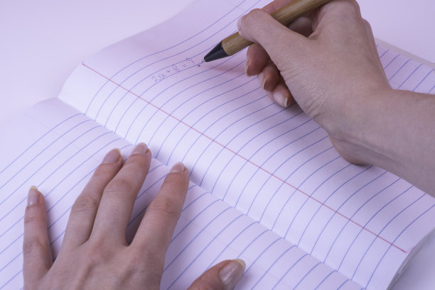 女人的手写在开放式作文笔记本，宽横线。图片下载