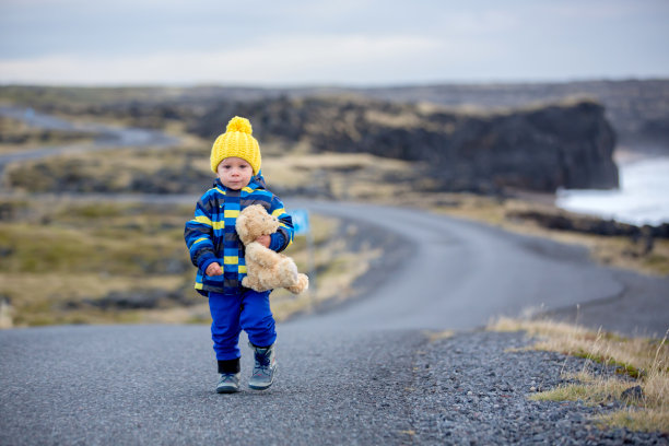 在冰岛的Snaefellsjokull国家公园里，孩子走在海边的一条弯曲的道路上，这是秋天的日落时分图片下载