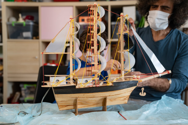 新冠肺炎疫情隔离期间，父子在画木模船图片下载
