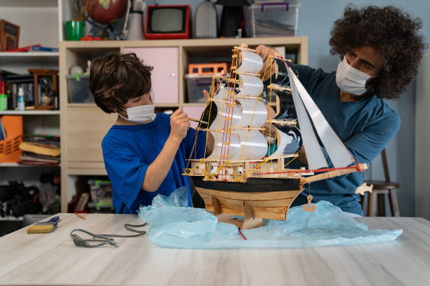 新冠肺炎疫情隔离期间，父子在画木模船图片下载