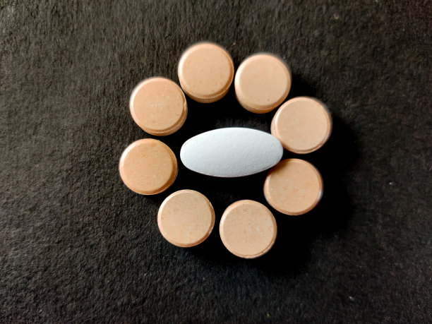 白色药丸周围是橙色药片。孤立在黑色背景上。图片下载