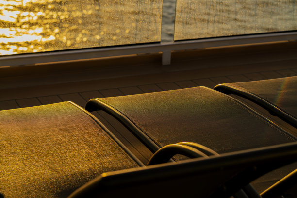 一排空的日光浴长椅上的游轮木制甲板日落时刻图片下载