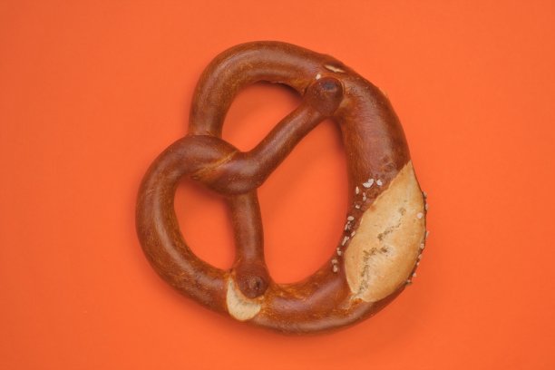 椒盐卷饼设置隔离在明亮的橙色背景。啤酒节节日的象征。传统的德国和阿斯特里安糕点。图片下载