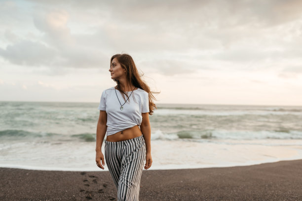 快乐的女人在海滩上欣赏美丽的日落图片下载
