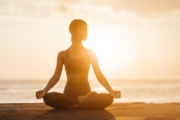日落时在海滩上做瑜伽。在海里做体式，享受生活的女人图片下载