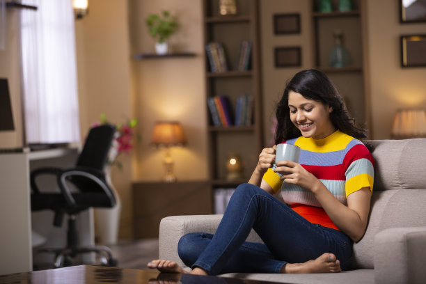 年轻女子坐在家里的沙发-库存照片图片下载