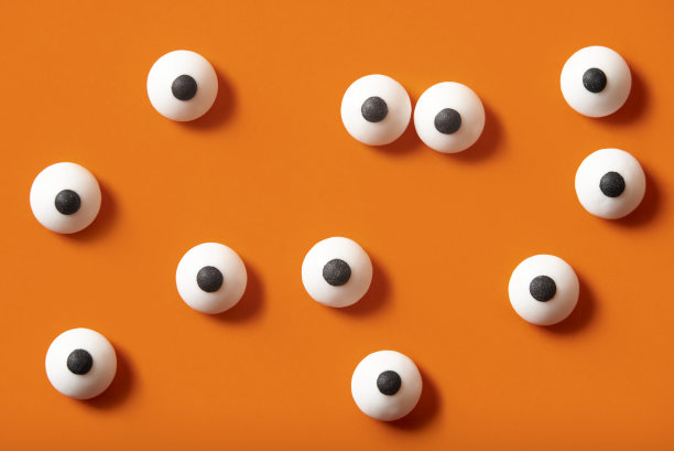 万圣节的背景，许多白色凸出的眼睛在橙色的背景上图片下载