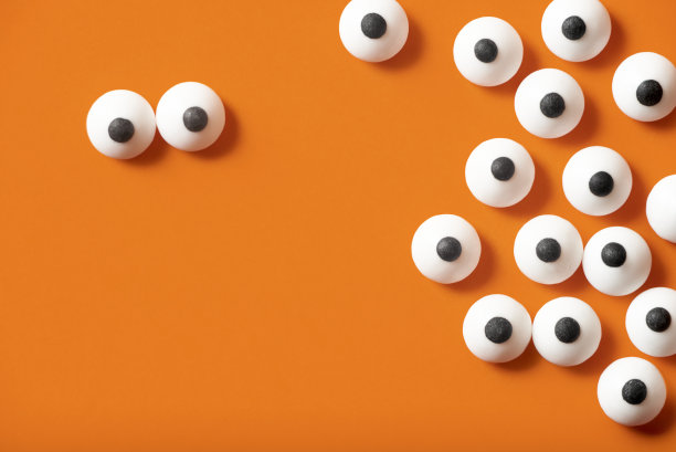 万圣节背景，许多白色凸出的眼睛在橙色的背景上，复制空间。图片下载