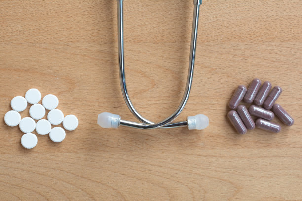 比较许多药丸的传统或现代医学与许多胶囊的传统，替代，草药接骨木在木质背景与医生医疗听诊器。图片下载