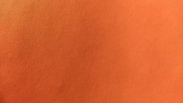 一张明亮的橙色厚纸。特写镜头。背景强烈的阴影。自然侧向照明。细腻的纸板或纸的质地。照明度的光梯度图片下载