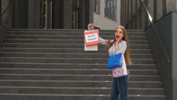 女孩展示黑色星期五购物袋上的题词，微笑，满意的低价购买图片下载