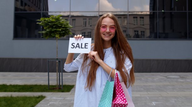 年轻时尚的女孩展示销售字题字文字，微笑着，看起来满意的低价图片下载