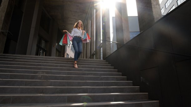 兴高采烈的女孩拿着购物袋从购物中心走出来，在黑色星期五买东西很开心图片下载