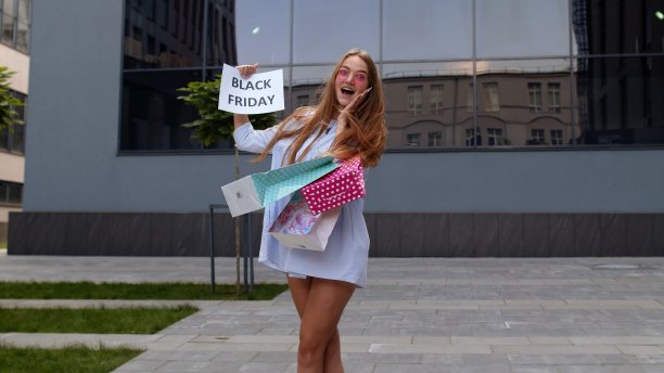 快乐的少女展示黑色星期五铭文，微笑着，看起来对低价很满意图片下载