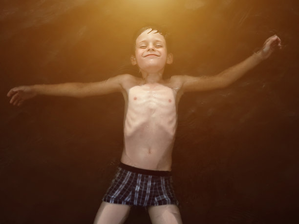 快乐的男孩躺在海里，微笑着享受着休息。图片下载