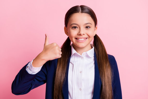 她的特写，她漂亮迷人，开朗愉快，自信的女孩显示拇指，推荐交易做广告，选择选择孤立的粉色柔和的颜色背景图片下载