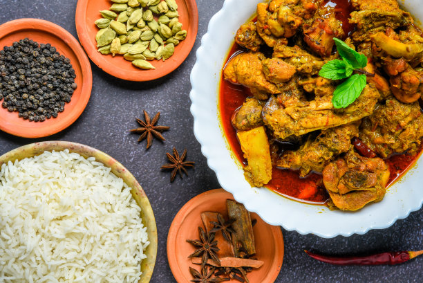 咖喱鸡或香料，辣红鸡腿片配香菜叶，安排在一个白色陶瓷碗与木制背景图片下载