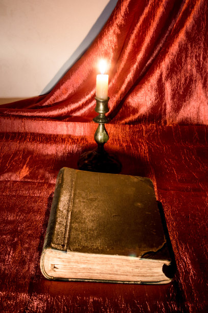 红色背景上的旧书和燃烧的蜡烛。图片下载