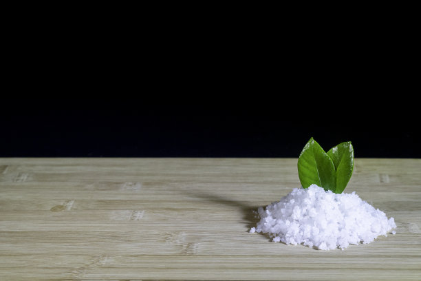 切菜板上的海盐堆用黑色的叶子装饰图片下载