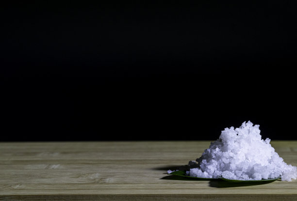 切菜板上的海盐堆用黑色的叶子装饰图片下载