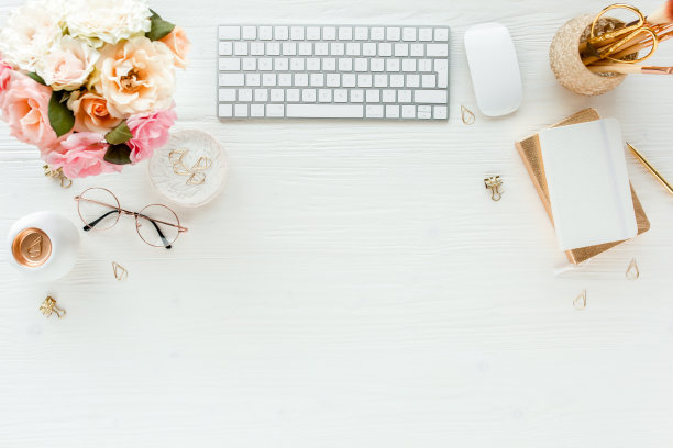 平放的女性办公桌。女性的工作空间，电脑，粉色玫瑰花，配件，金色日记，眼镜在白色的背景。俯视图图片下载
