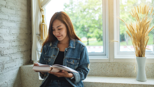 一个美丽的亚洲女人坐在家里看书图片下载