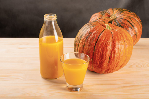 杯子里的新鲜南瓜汁和橙色的南瓜。健康美味的食品理念。秋天的收获。图片下载