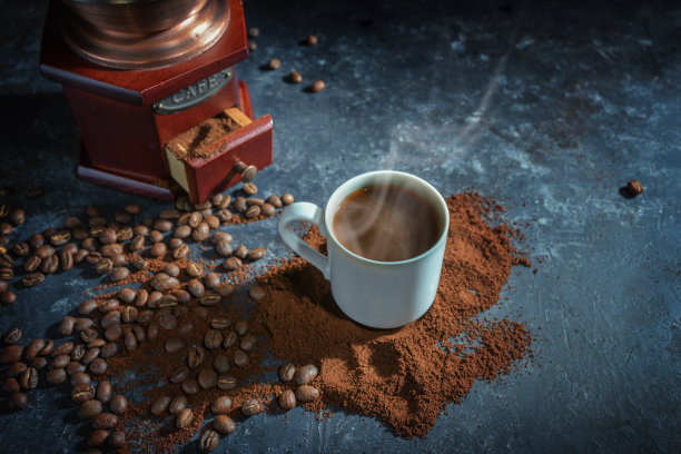 咖啡杯上有热气腾腾的咖啡粉和烘豆，放置在老式研磨机前，深色背景有拷贝空间，图片下载