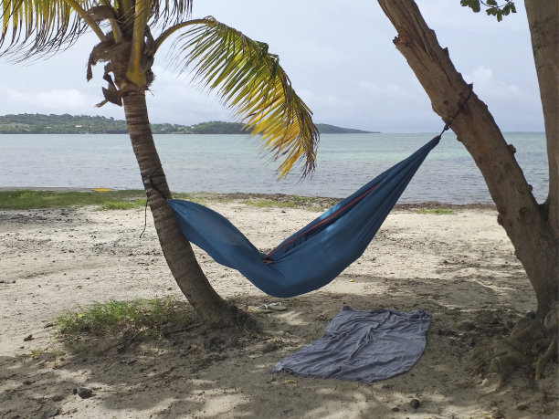 在加勒比海岸边的蓝色吊床上休息，碧蓝的海水。加勒比和热带景观背景图片下载
