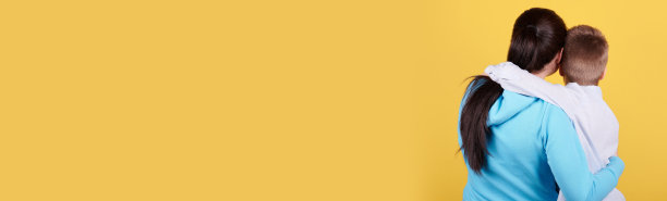 黑发男孩和妈妈坐在一起，拥抱，爱，家人。隔离在黄色背景，复制空间模板，横幅。图片下载