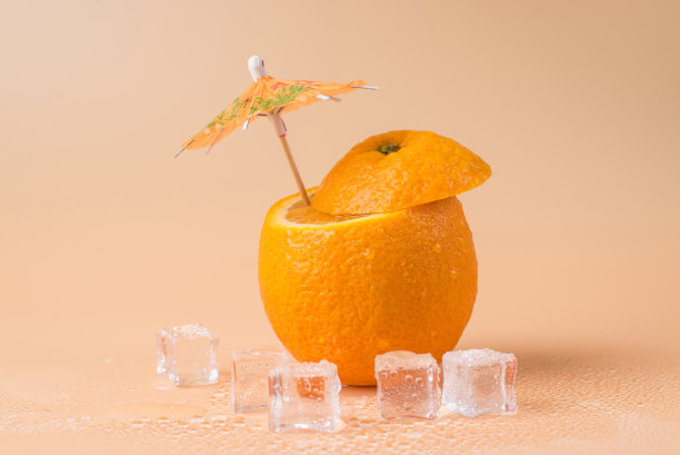 夏季的概念。特写照片切橙与鸡尾酒伞在它和冰块孤立在沙地背景图片下载