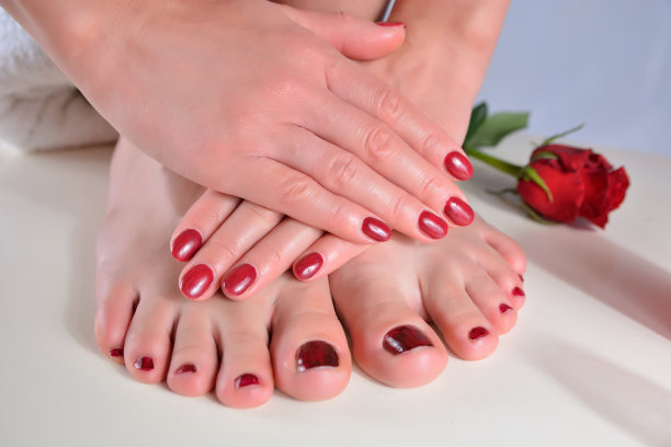 在美容工作室为女性的脚和手做红色美甲和足疗图片下载