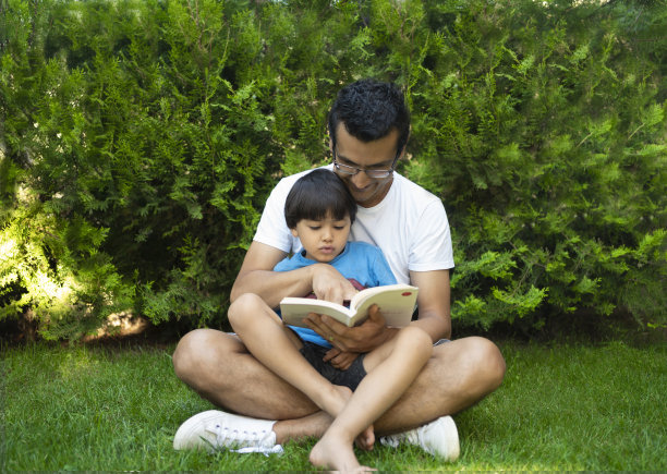 小男孩和他的爸爸在花园里看书图片下载