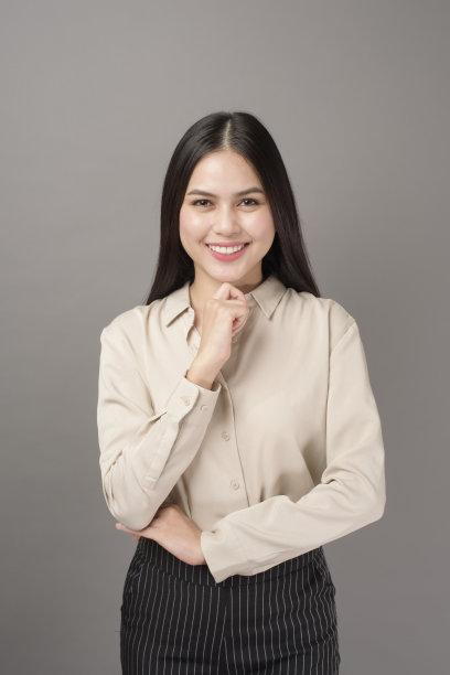 肖像美丽的商业女人微笑在灰色的背景图片下载