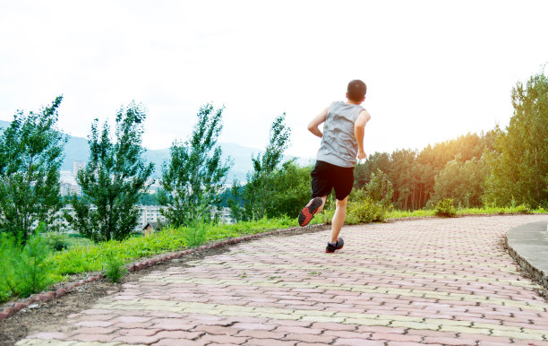 男人在公园的砖路上奔跑图片下载
