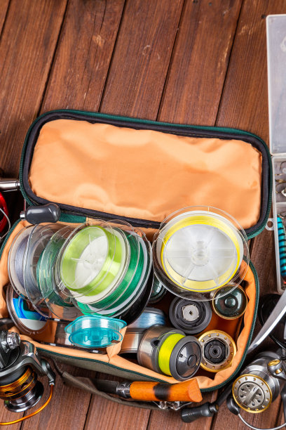 不同的钓具与鱼饵和卷轴在木制的棕色背景与文字的地方。广告及出版设计。图片下载