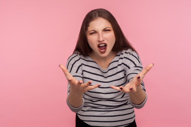 你想要什么?肖像愤怒愤怒的女人在条纹运动衫举起手，看着愤怒图片下载