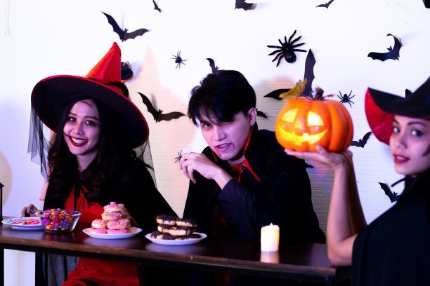 亚洲朋友在晚会上穿着女巫服装，吃着食物喝着杰克灯图片下载