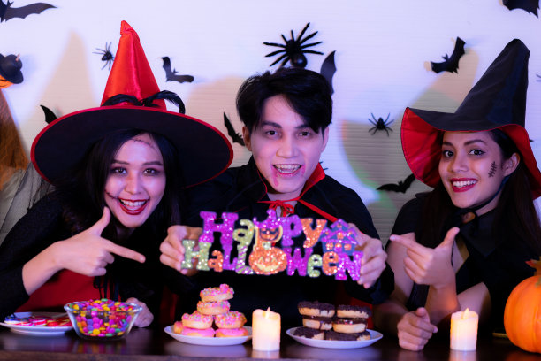 亚洲朋友在晚会上穿着女巫服装，吃着食物喝着杰克灯图片下载