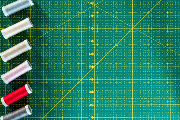 在绿色裁剪垫上的许多彩色线的俯视图。缝纫平铺与复制的空间图片下载
