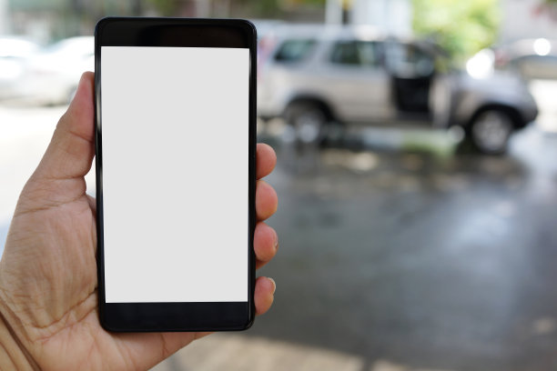 一名男子在室外停车场边开车边用智能手机图片下载