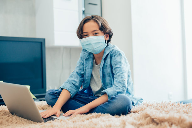 男孩穿着便服坐在家里的床上图片下载