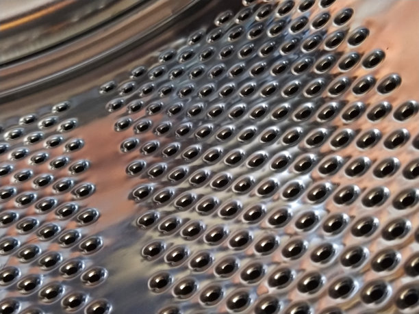 洗衣机的滚筒从里面。闪亮的金属罐，有孔和凸起。不锈钢表面带孔，由不锈钢板材制成。洗衣机的内部视图图片下载