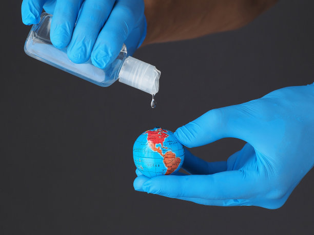 消毒瓶在流行。用医用手套中的酒精凝胶处理地球。冠状病毒的消毒。图片下载