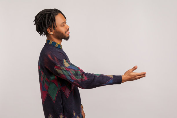 侧面肖像友好的非洲人与雷鬼发伸展手欢迎客人与牙齿的微笑在脸上，很高兴见到你图片下载