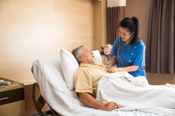 医生正在用听诊器听诊一位老年病人的心脏。在医院的病房里图片下载