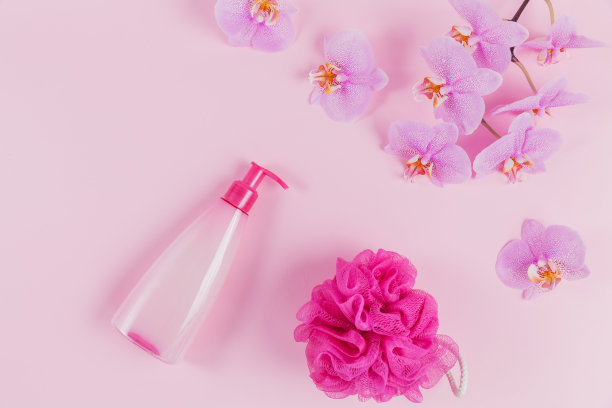 化妆皂、洗发水或沐浴露、粉红色海绵和紫色兰花花的塑料瓶。水疗与健康概念图片下载