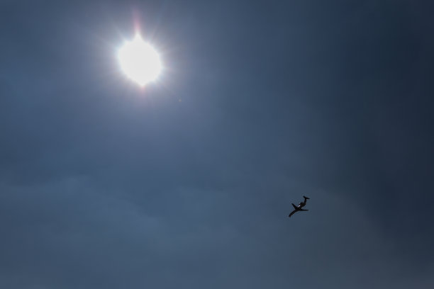 天空中一架飞机的剪影，太阳就在它的上方图片下载