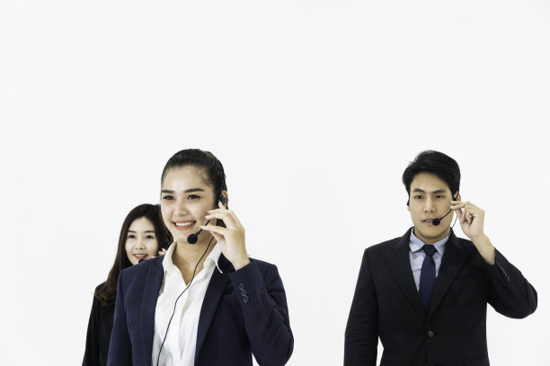 年轻的亚洲商务呼叫中心的男男女女戴着耳机准备为客户支持工作，在白色背景上放短信或拷贝空间。咨询电话营销及协助服务图片下载