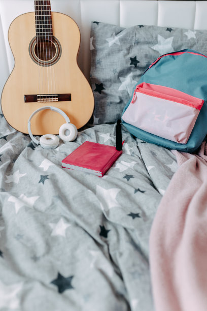 学习后的学生房间。床上放着吉他、背包、耳机和笔记本。图片下载